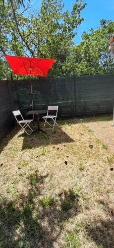 une table et deux chaises avec un parapluie rouge dans l'établissement Maisonette Bezouce, Calme et accueillant, à Bezouce