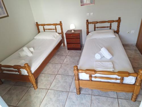 two twin beds in a room with a table at 85 sqm Apartments New Panorama ELECTRIC CAR ΦΩΡΤΗΣΗΣ STATION in Paralion astros
