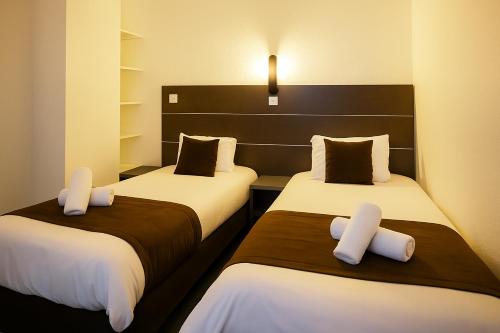 two beds in a hotel room with white pillows at Hotel & Spa Gil de France Cap d'Agde in Cap d'Agde