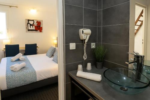 a bathroom with a bed and a sink and a phone at Hotel & Spa Gil de France Cap d'Agde in Cap d'Agde