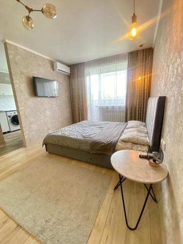 una camera da letto con un letto, un tavolo e una televisione di Стильные апартаменты со свежим ремонтом на ЖД вокзале a Qostanay