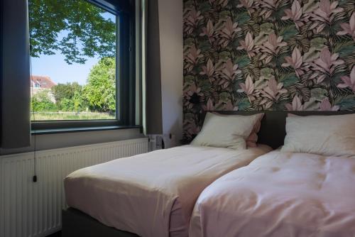a bedroom with a bed and a window with a floral wallpaper at Vakantiehuisje De Barones in Middelburg