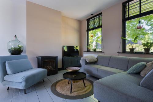 a living room with a couch and chairs and a fireplace at Vakantiehuisje De Barones in Middelburg
