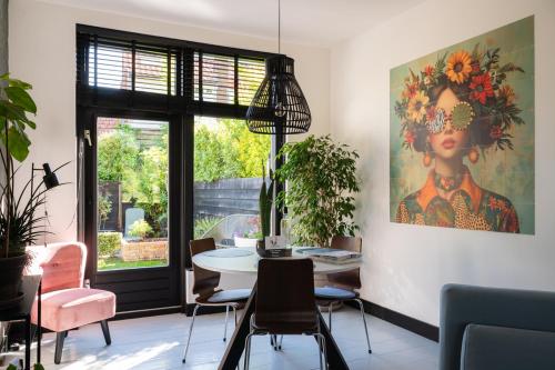 a dining room with a table and chairs and a painting at Vakantiehuisje De Barones in Middelburg
