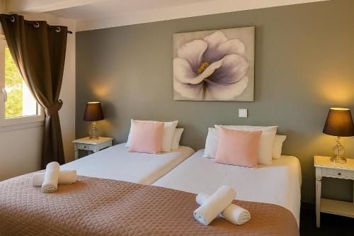 two beds in a room with two white beds at Hotel & Spa Gil de France Cap d'Agde in Cap d'Agde