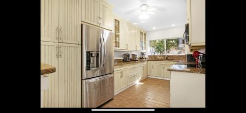 Una cocina con gabinetes blancos y un refrigerador de acero inoxidable. en Newly Renovated Fort Lauderdale Pool Home 3BR and 3 and a half baths, en Fort Lauderdale