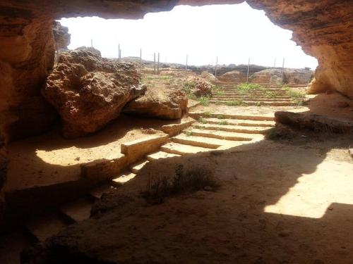 an entrance to a cave with rocks and stairs at Dar Shayran in El Haouaria