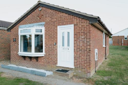a brick house with a white door and a window at The Bird's Nest by Sheppey Stays in Sheerness