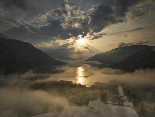 a view of a river in the middle of a valley with clouds at Monachyle Mhor Hotel in Lochearnhead