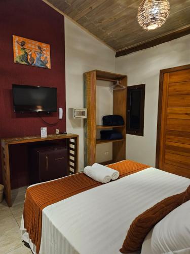 a hotel room with a bed and a tv at Pousada de Charme Emirados in Ilhabela