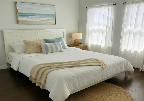 a white bedroom with a large white bed with pillows at Newly Build House!Island Charm Balcony Vibes 3 Min to Beach in Galveston