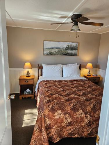 a bedroom with a bed and two night stands with lamps at CARLETON INN & COTTAGES in Bridgetown