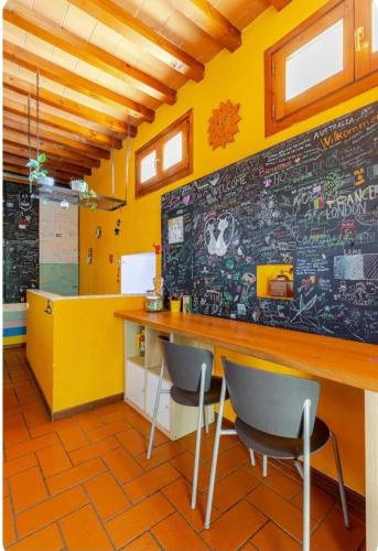 a room with a yellow wall with a counter and chairs at Casa Gelso in Scandicci