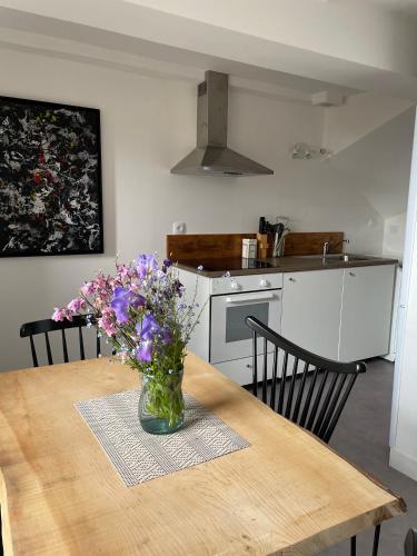 une cuisine avec une table avec un vase de fleurs dessus dans l'établissement APPARTEMENTS DE CHARME dans quartier médiéval, à Domfront