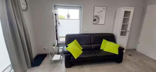 LangsurFerienwohnung am Wingertsberg的客厅里有一把黑色皮椅，上面放着黄色靠垫。