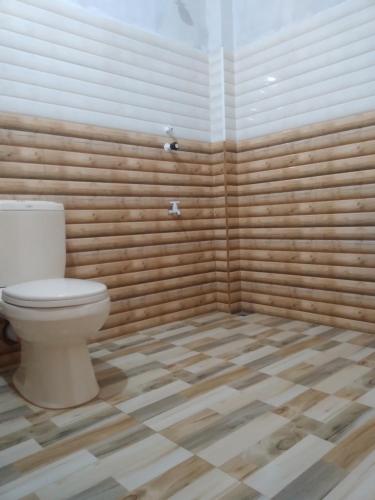a bathroom with a toilet in a room with wooden walls at Peacock Residence & Cabana's in Tangalle