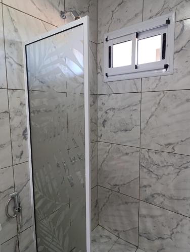 a shower with a glass door and a window at Alojamiento colibrí in La Porteña