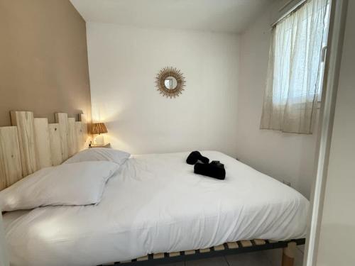 - une chambre blanche avec un lit doté d'un sac noir dans l'établissement Valras'Loc Cap Horn, à Valras-Plage
