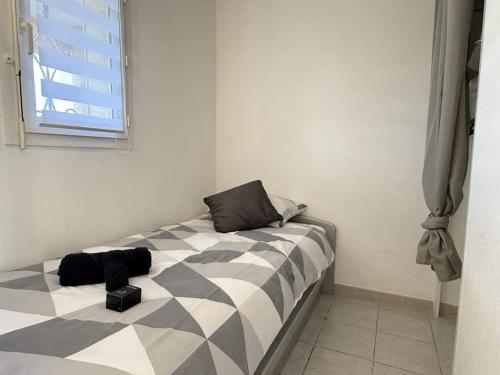 une chambre avec un lit avec une couette noire et blanche dans l'établissement Valras'Loc Cap Horn, à Valras-Plage