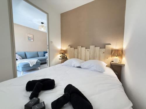 - une chambre avec un lit blanc et 2 serviettes noires dans l'établissement Valras'Loc Cap Horn, à Valras-Plage