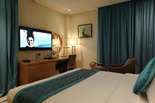 a hotel room with a bed and a flat screen tv at Meshal Hotel in Manama