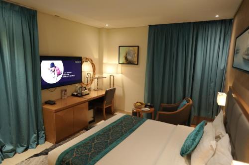 a hotel room with a bed and a desk and a television at Meshal Hotel in Manama