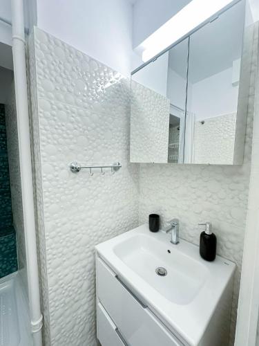 a white bathroom with a sink and a mirror at Sunrise Apartments City Center in Bucharest