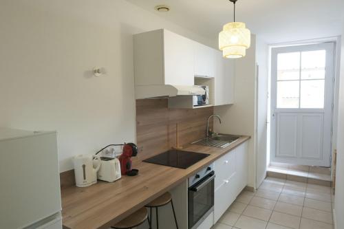 une cuisine avec des armoires blanches et un comptoir en bois dans l'établissement La Terrasse - Centre-ville proche gare, à Valence