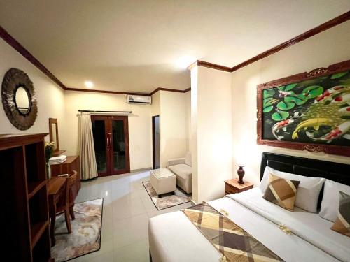 a hotel room with a bed and a living room at Guesthouse Gusti Putu Oka in Ubud