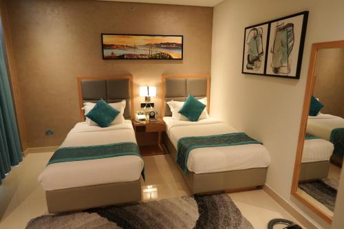 a hotel room with two beds and a mirror at Meshal Hotel in Manama
