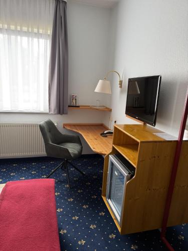 a room with a desk with a television and a chair at Hotel hArz7 in Seesen