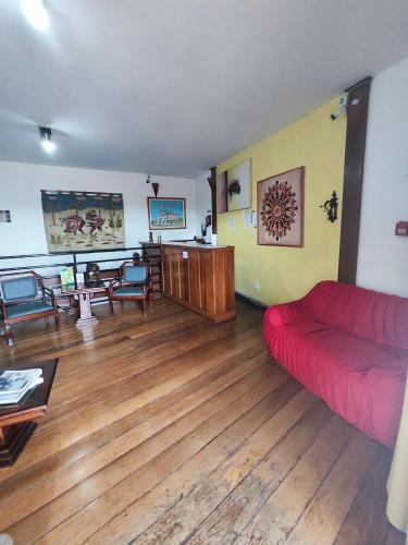 a living room with a red couch and wooden floors at Pousada Flor de Lis in Diamantina
