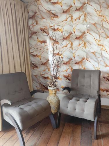 two chairs and a vase in a room with a wall at Pousada Flor de Lis in Diamantina
