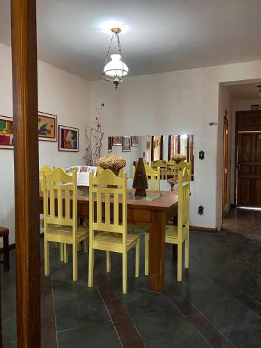 a dining room with a wooden table and yellow chairs at Pousada Flor de Lis in Diamantina