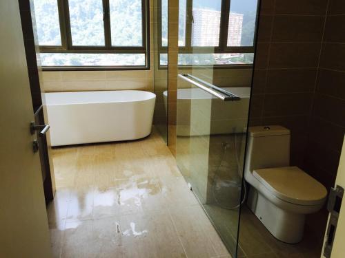 a bathroom with a tub and a toilet and a window at By the Sea PENTHOUSE duplex in Batu Ferringhi