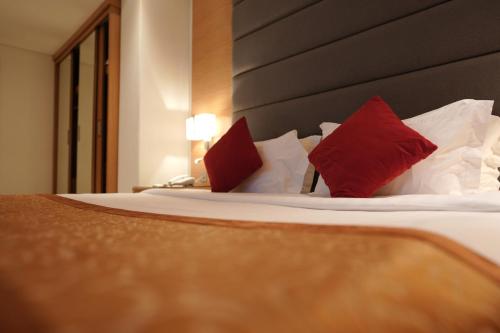 a bedroom with a bed with red and white pillows at Meshal Hotel in Manama