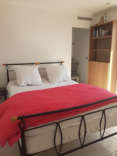 - un lit avec une couverture rouge et 2 oreillers blancs dans l'établissement L Olivier, à Gattières