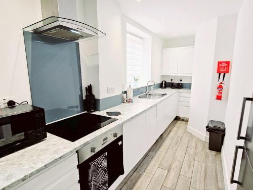 a white kitchen with a sink and a counter top at The Maple Suite in Farnham