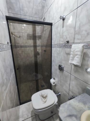 a bathroom with a shower and a white toilet at Pousada Flor de Lis in Diamantina