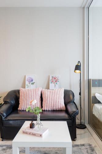 a living room with a black leather couch and a white coffee table at 曼谷繁华地区公寓 免费上网 家居家电齐全 in Ban Na Song