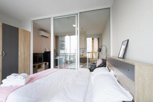 a bedroom with a large white bed and glass walls at 曼谷繁华地区公寓 免费上网 家居家电齐全 in Ban Na Song