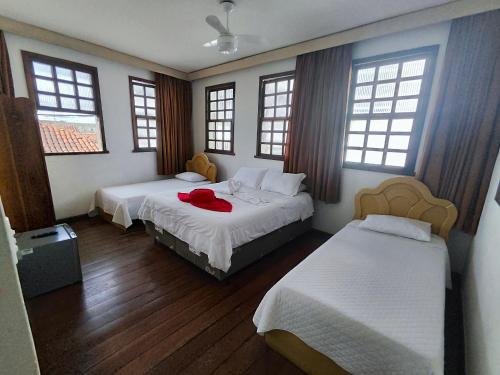 a bedroom with two beds and two windows at Pousada Flor de Lis in Diamantina