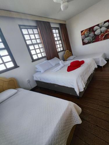 two beds in a bedroom with two windows at Pousada Flor de Lis in Diamantina
