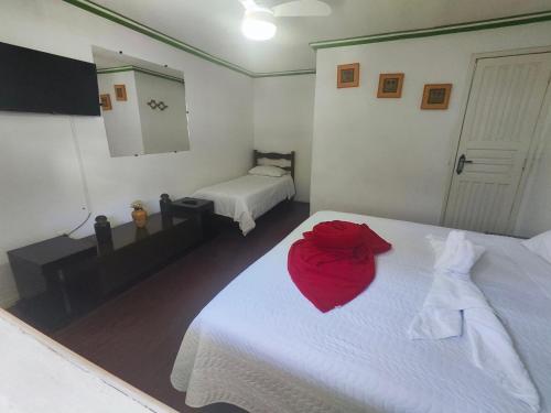 a bedroom with a white bed with a red dress on it at Pousada Flor de Lis in Diamantina