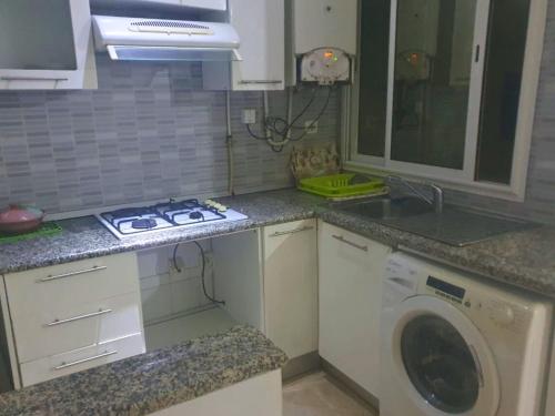 a kitchen with a stove and a washing machine at Ennasr 1- S1 Calme et Magnifique - Proche Hedi Nouira et Commodités in Ariana