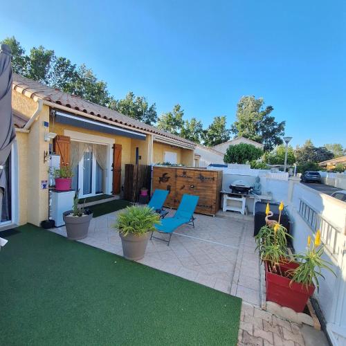 une cour avec une terrasse meublée de chaises et de plantes dans l'établissement Pitchounette, à Vias