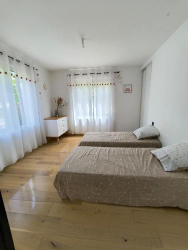 - 2 lits dans une chambre dotée de murs blancs et de parquet dans l'établissement villa Mia Minervois, à Olonzac