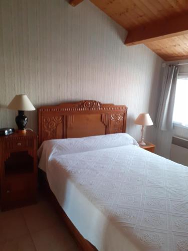 - une chambre avec un lit en bois avec des draps blancs et une fenêtre dans l'établissement Maison Les Sables D'olonne, à Les Sables-dʼOlonne