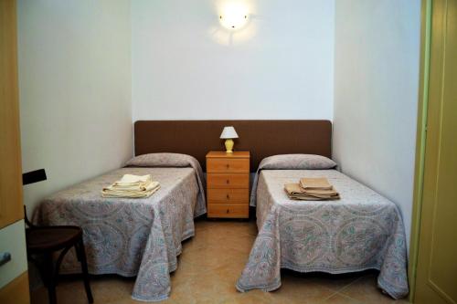 a room with two beds and a dresser with a lamp at I due Tesori in San Cesario di Lecce