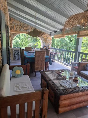 - un salon avec une table et des chaises sur une terrasse couverte dans l'établissement Demeure de charme OLIVIRA, à Vesseaux